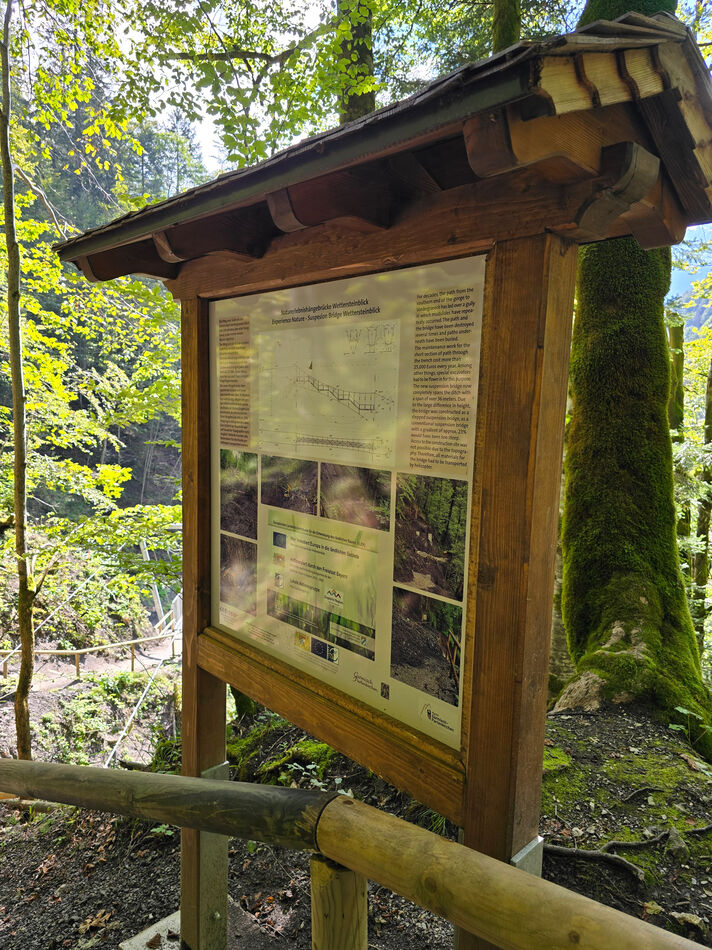 Blick auf ein Wanderschild bei der Naturerlebnishängebrücke Wettersteinblick